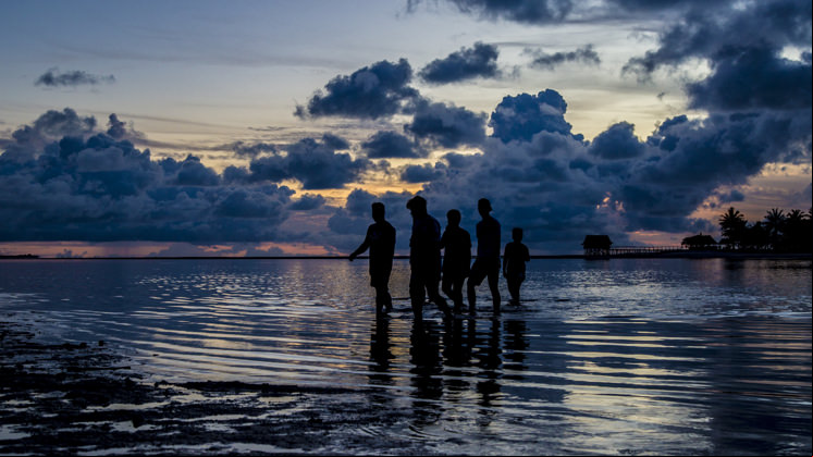 Um grupo de pessoas cruza a lagoa em Tarawa, Kiribati.
