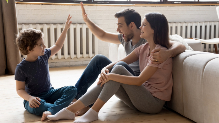 Father, mother and little son sitting on a warm wooden floor, relaxing together in their own heated apartment.